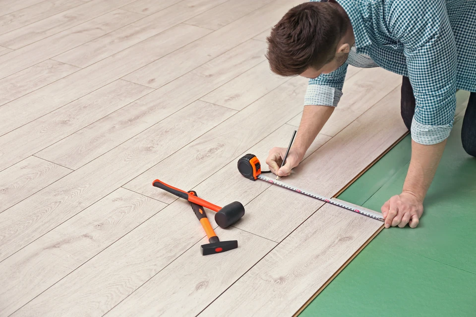 Homme installant de nouveaux sols stratifiés en bois