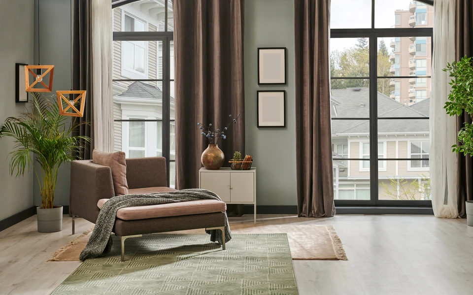 Salon moderne avec fauteuil marron et repose-pieds, plaid texturé, plantes vertes dans pots décoratifs