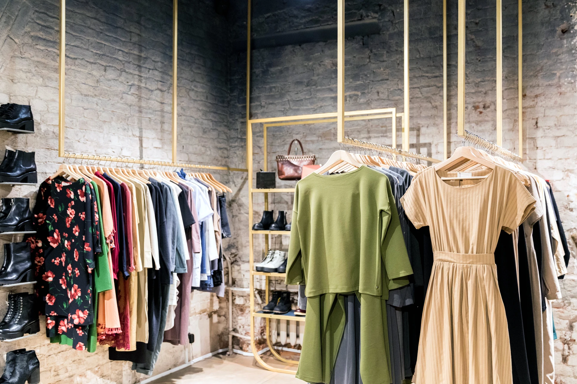 Intérieur d'une boutique de mode féminine avec vêtements suspendus sur portants métalliques dorés