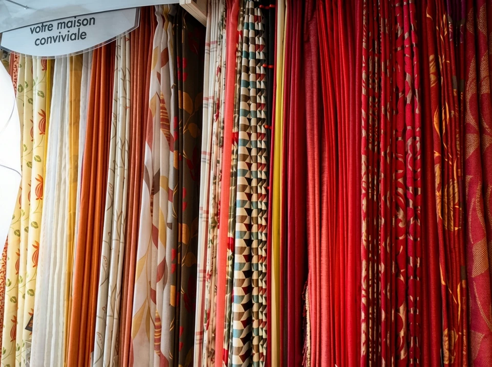 Intérieur boutique de vêtements avec portant métallique présentant collection textile colorée organisée par teintes